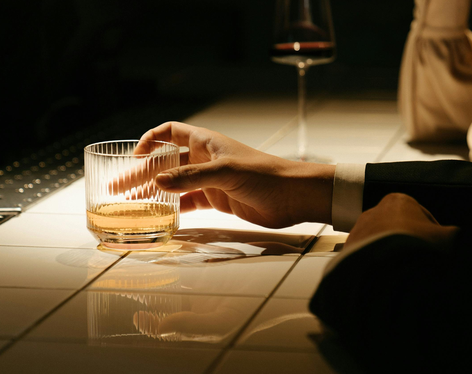 person sitting holding elegant glass of whiskey